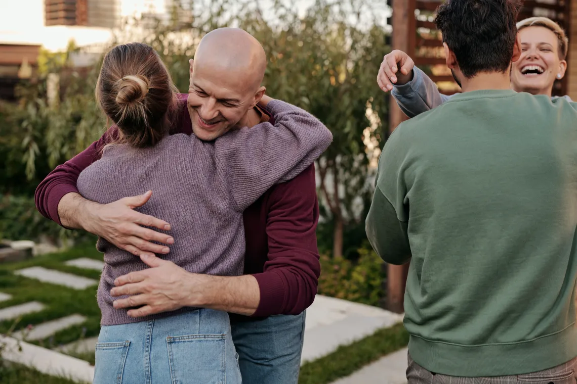 2 people walking towards 2 other people and hugging